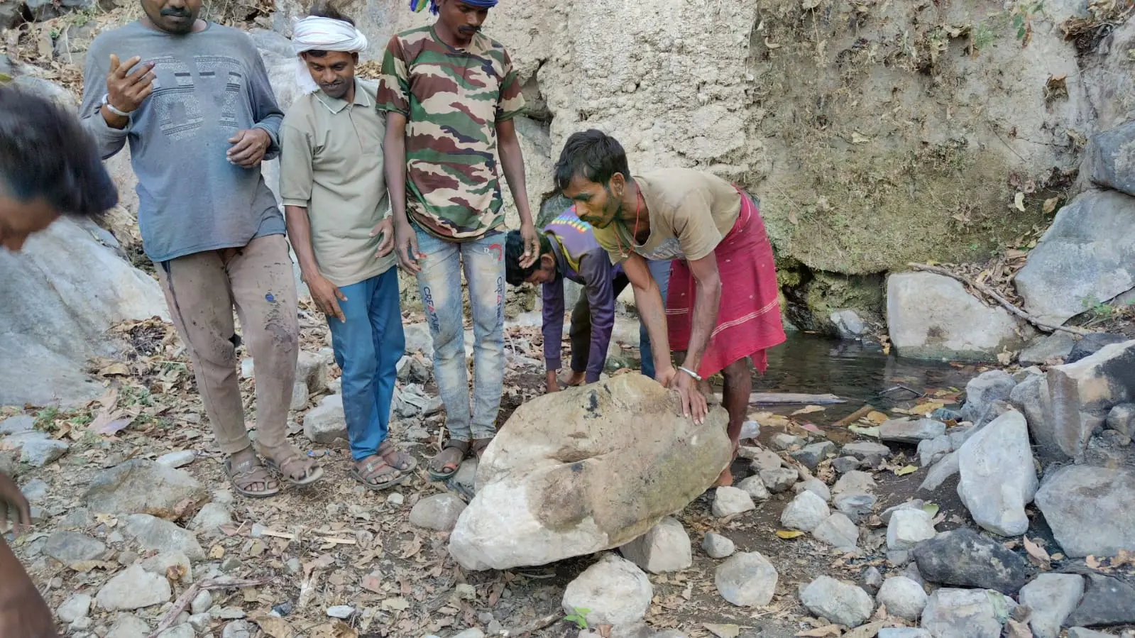 सातपुडा टेकड्यांमध्ये काही लोक पाण्याचा स्रोत सुधारण्यासाठी दगड हलवत आहेत.
