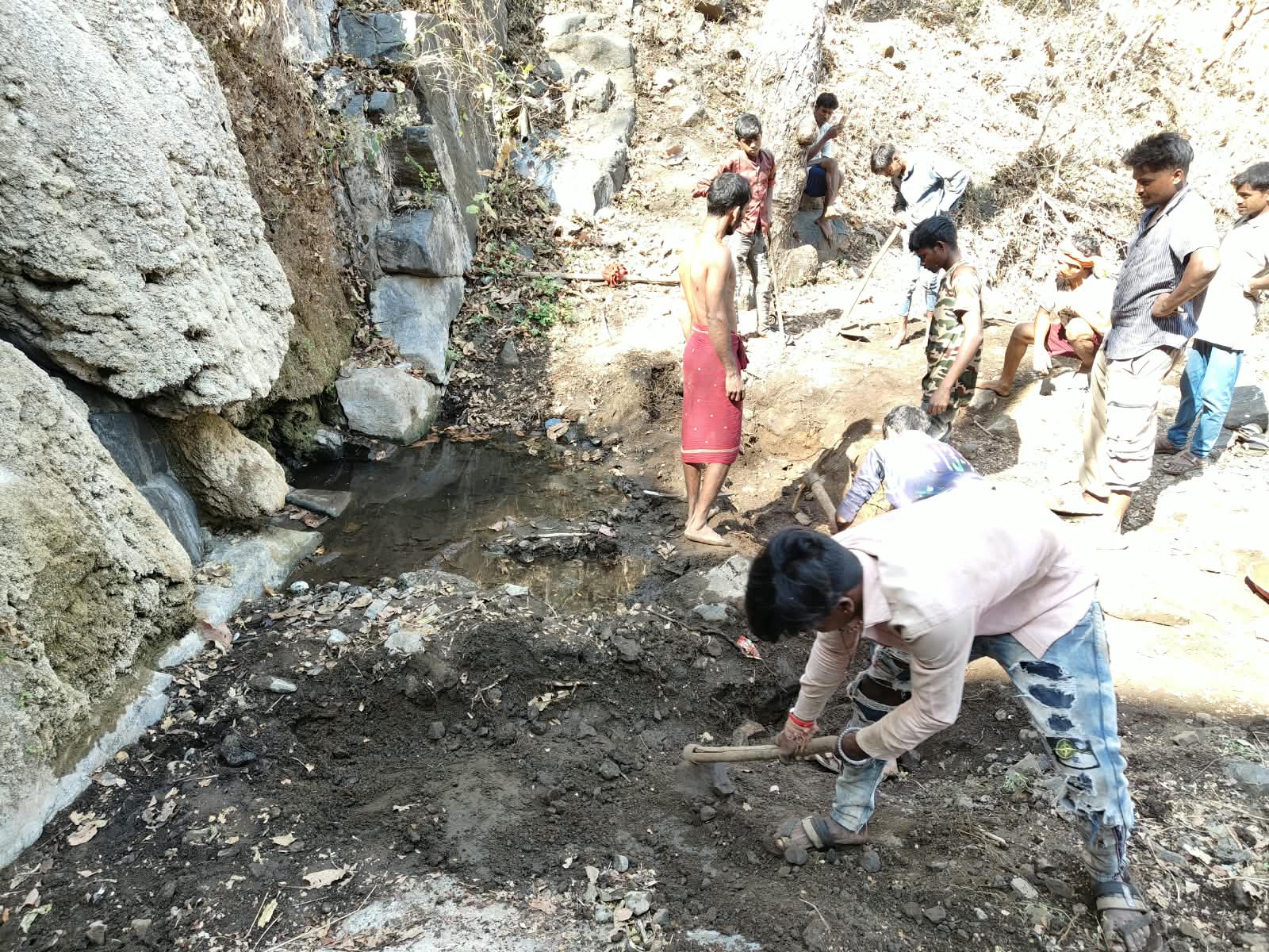 सतपुडा डोंगरात काही लोक माती आणि पाणी एकत्र करत आहेत.