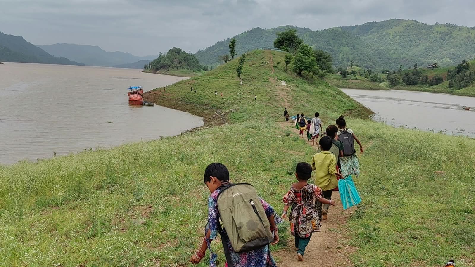 मुले एका हिरव्या टेकडीवरून चालत आहेत.