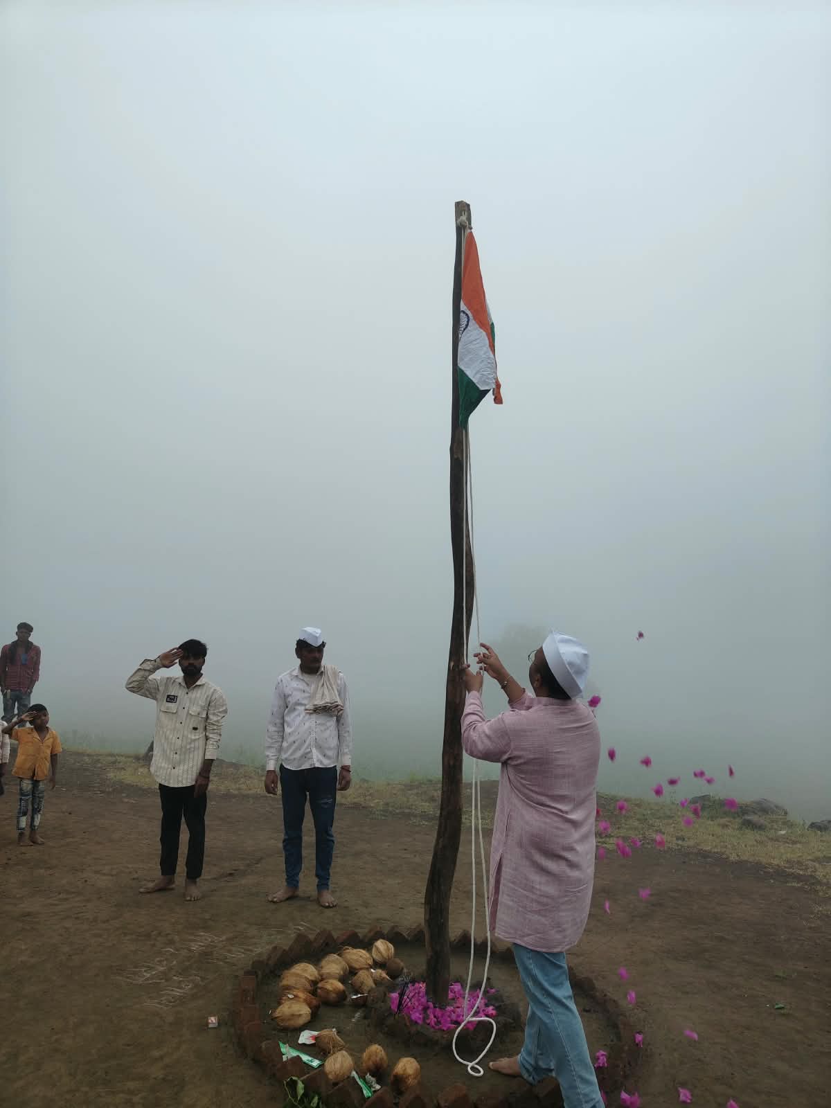 एक व्यक्ती सातपुडा टेकड्यांवरील धुके असलेल्या वातावरणात राष्ट्रध्वज फडकावत आहे.