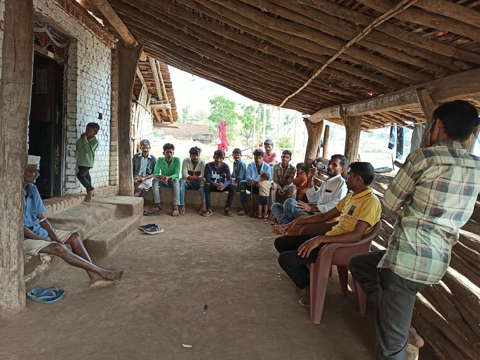 सातपुडा भागातील एका घराजवळ लोक एकत्र बसले आहेत.