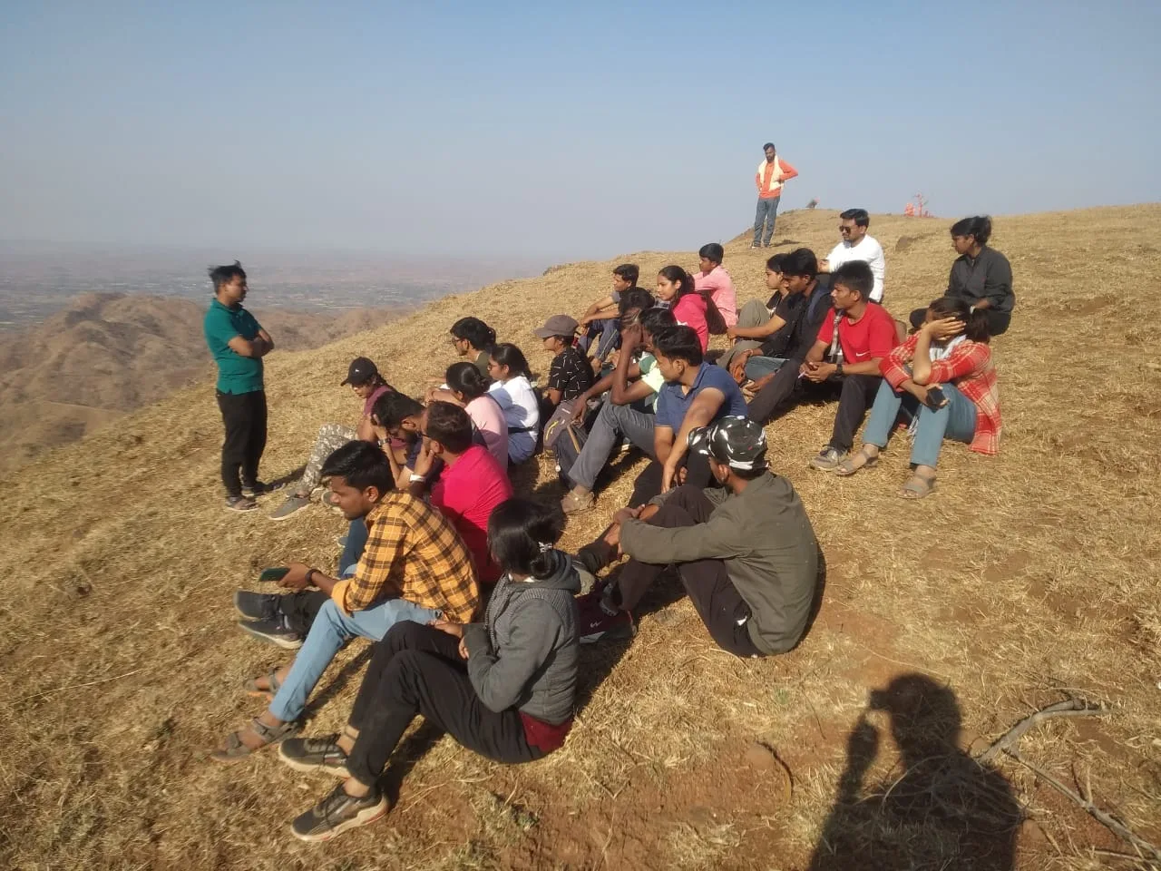 सतपुडा डोंगरांवर बसलेले लोक आणि एक व्यक्ती उभी आहे.
