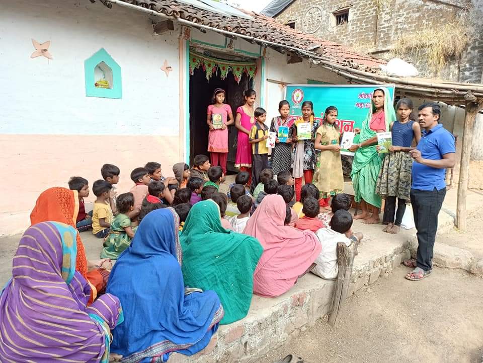 यंग फाउंडेशनचे कार्यकर्ते मुलांसमोर पुस्तके वाटत आहेत.