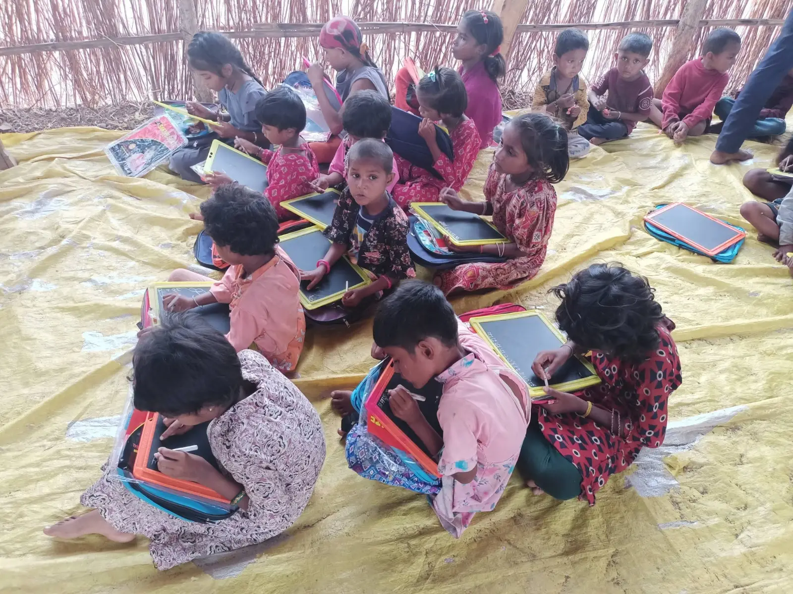 सतपुडा हिल्समध्ये मुले चटईवर बसून पाटीवर लिहीत आहेत.