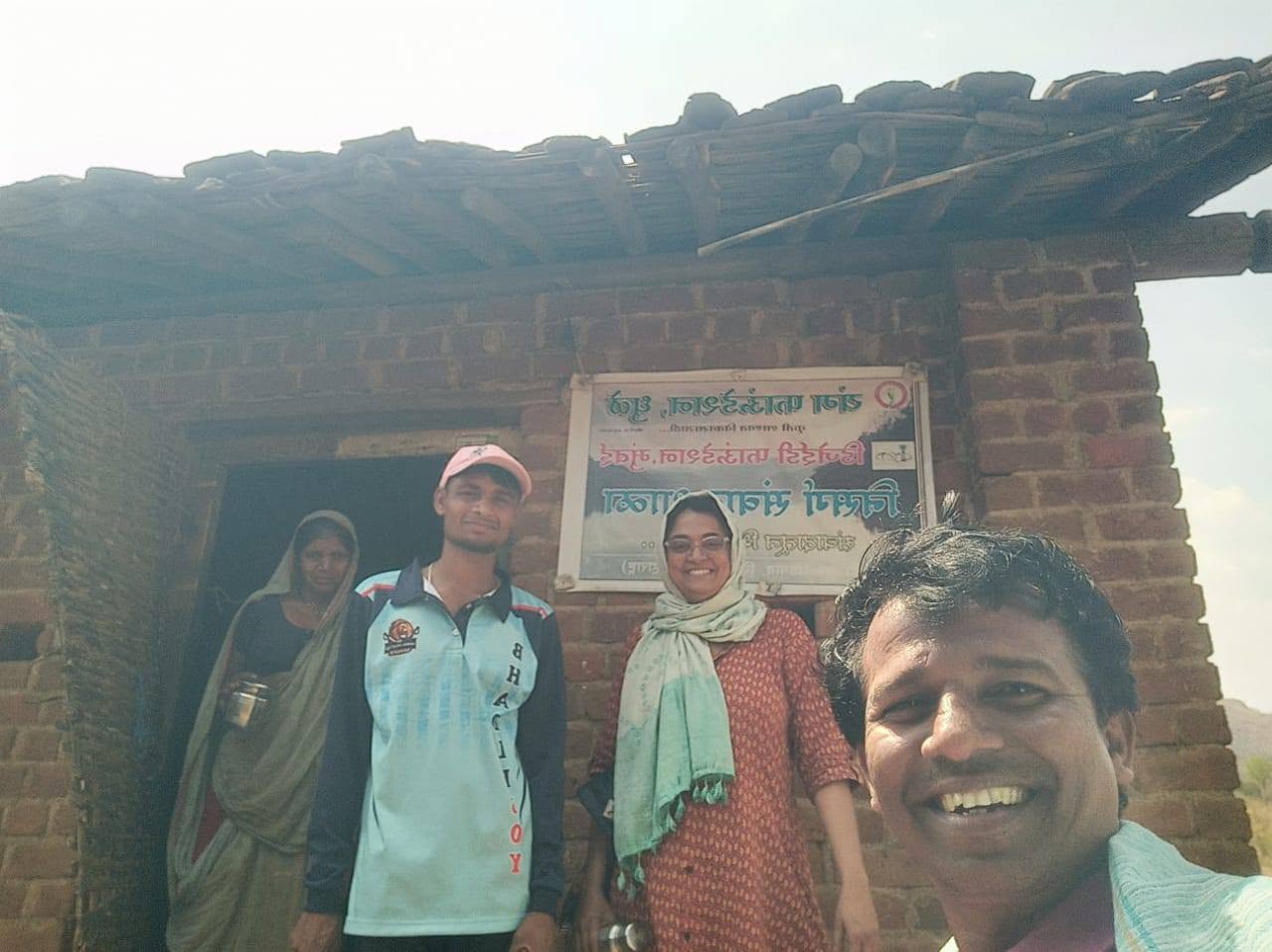 सतपुडा डोंगरांवरील एका विटेच्या घराबाहेर उभे असलेले यंग फाऊंडेशनचे लोक.