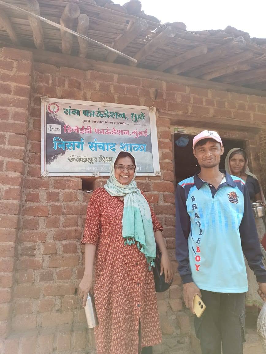 यंग फाऊंडेशनच्या फलकासमोर दोन व्यक्ती उभे आहेत.