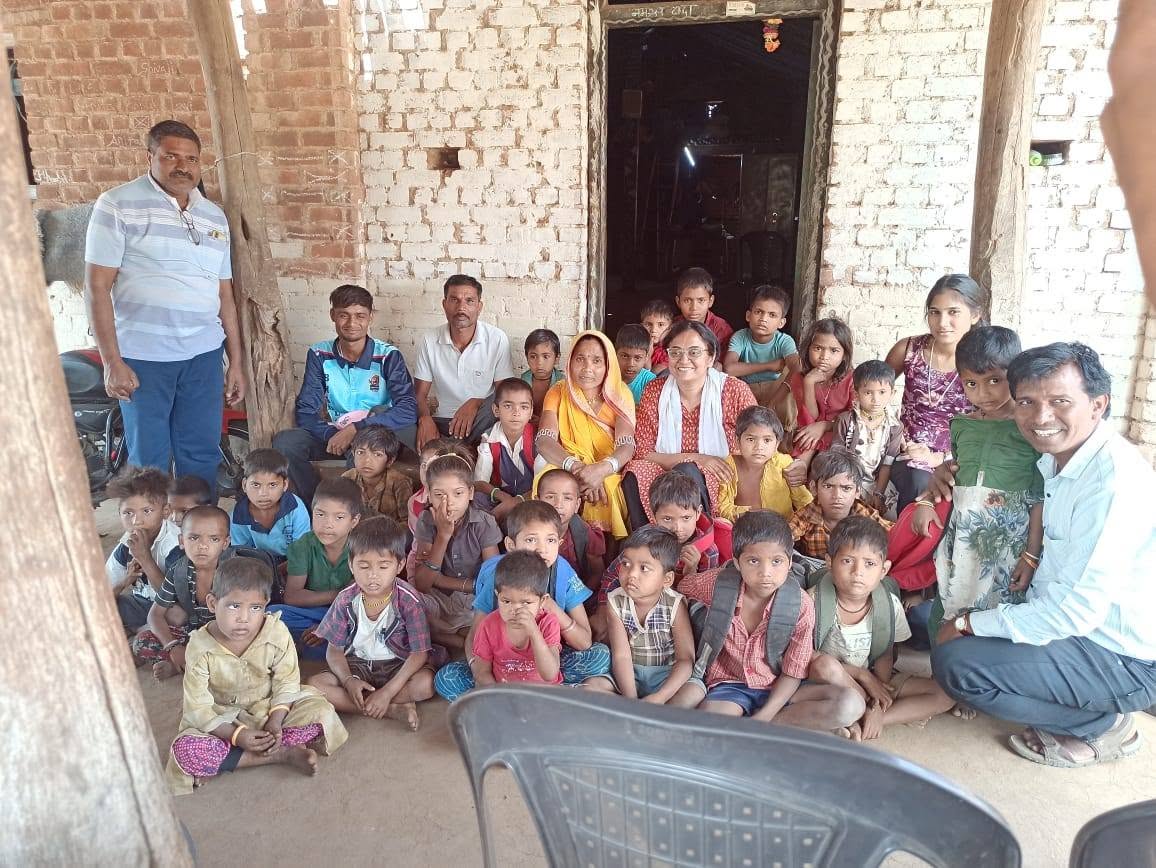 यंग फाऊंडेशनच्या कार्यात सहभागी झालेली मुले आणि नागरिक घराबाहेर एकत्र बसले आहेत.