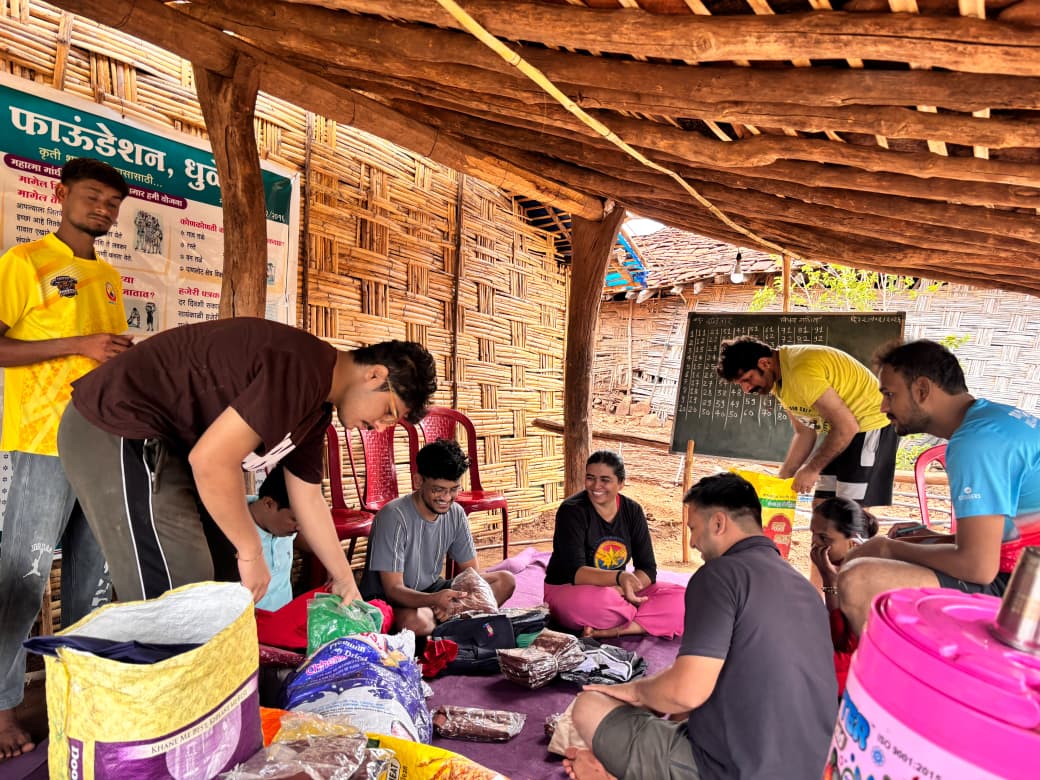 यंग फाऊंडेशनचे कार्यकर्ते एका शेडखाली बसून मदत साहित्याची वर्गवारी करत आहेत.