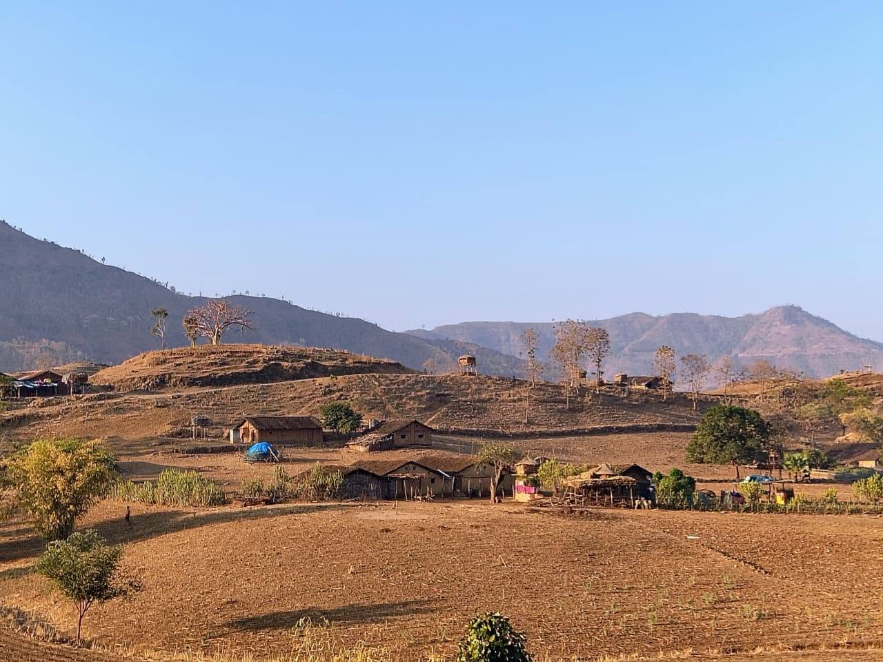 डोंगराळ प्रदेशात वसलेले छोटे घर आणि शेतजमीन.